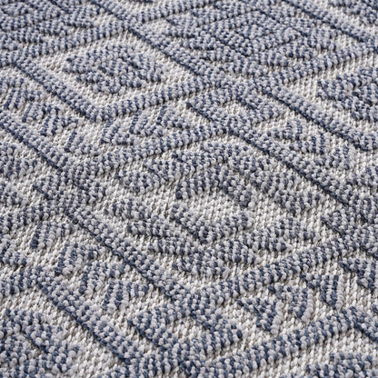 A close-up of the Guros - Traditional Indoor / Outdoor Area Rug, showcasing its blue and white geometric diamond pattern with a textured, slightly raised surface.