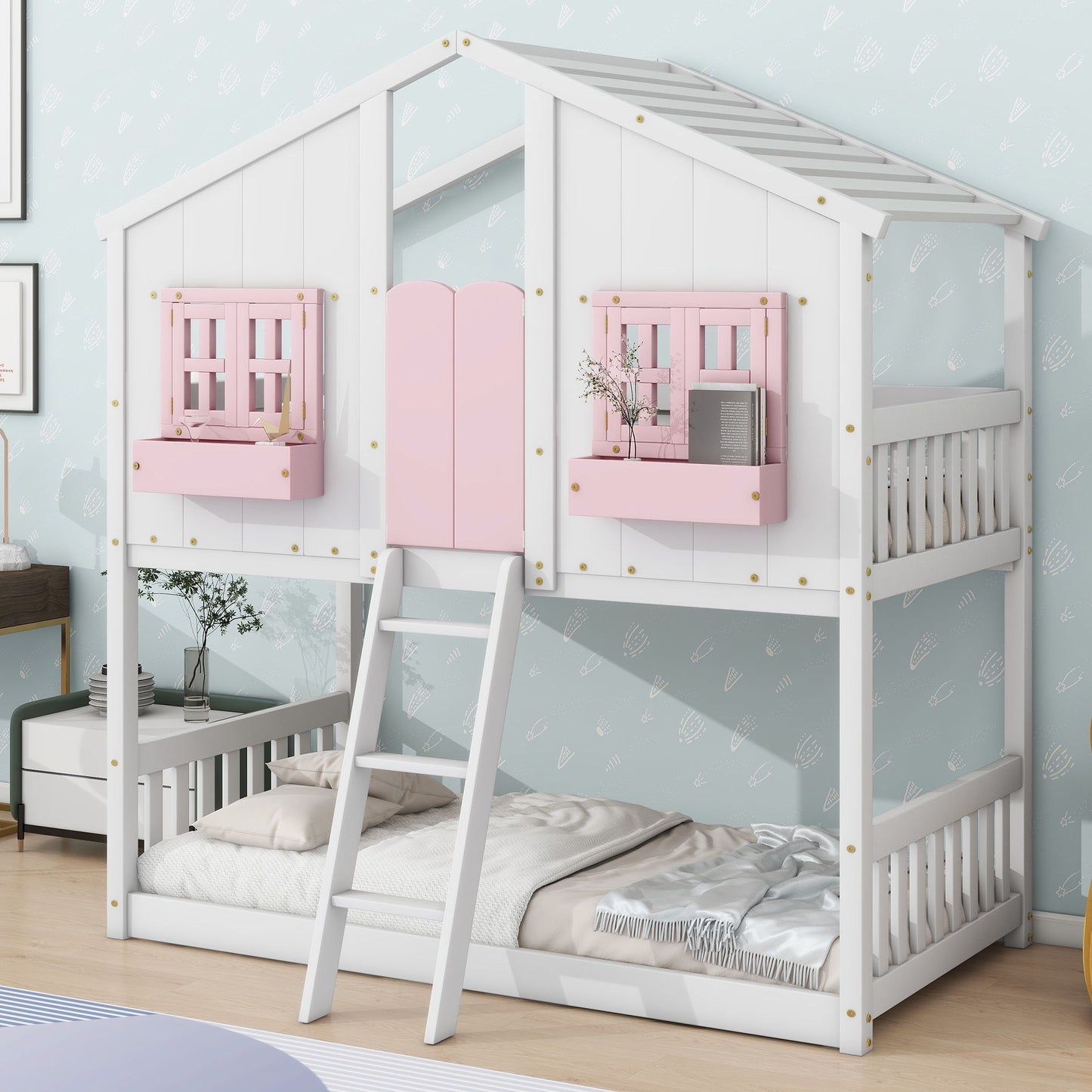 The House Bunk Bed features a roof, windows with boxes, a door, safety guardrails, and a ladder, styled like a playhouse. It is shown in white with pink window shutters and bedding on the lower bunk against a light blue patterned wall.