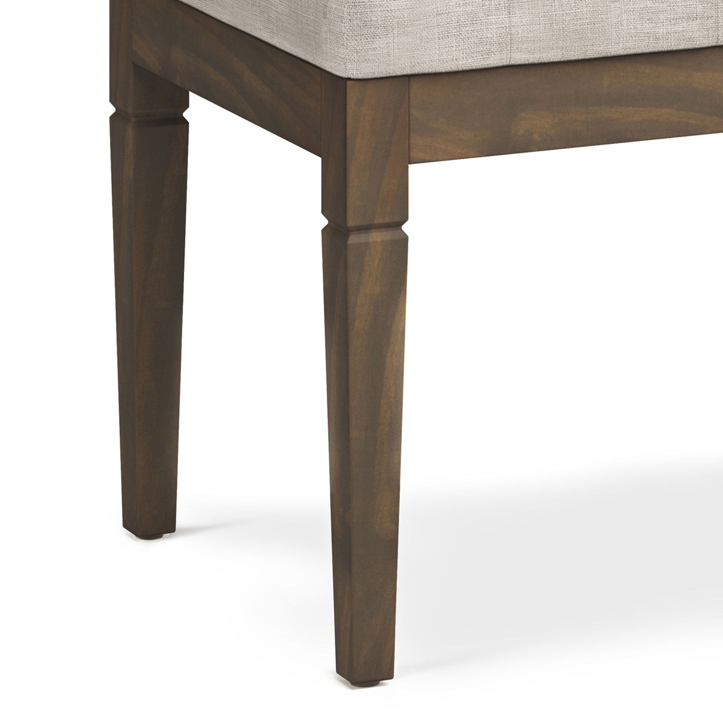 Close-up view of the corner of the Waverly - Upholstered Tufted Ottoman Bench, featuring tapered wooden legs and a light-colored upholstered seat cushion.