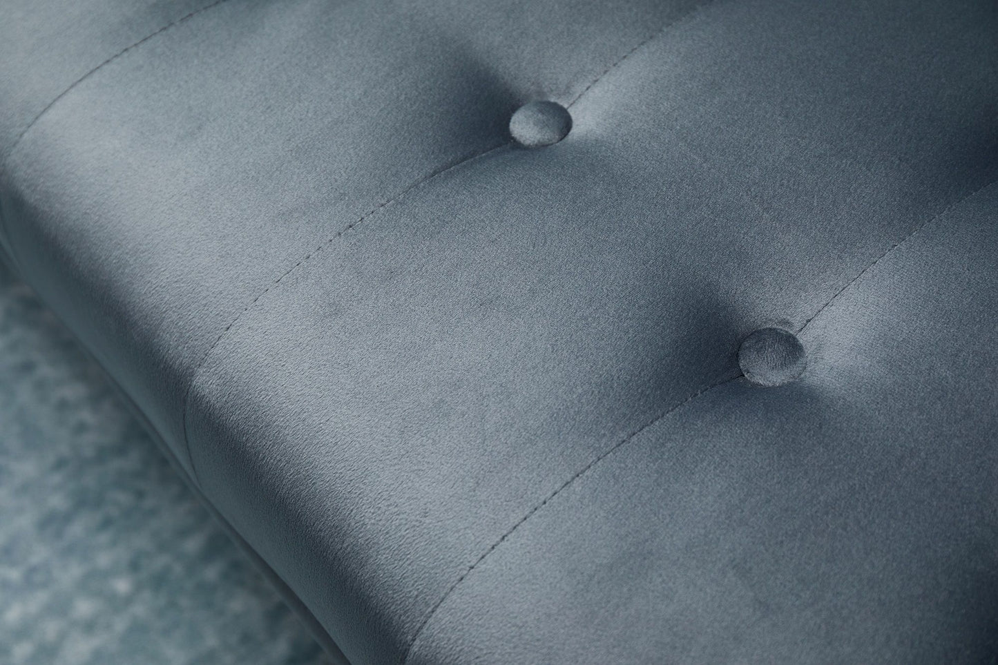 Close-up of the gray upholstered cushion on the Comfort Compact Design Sofa Bed, featuring visible stitching and two round tufted buttons. A textured carpet is partially visible at the edge.
