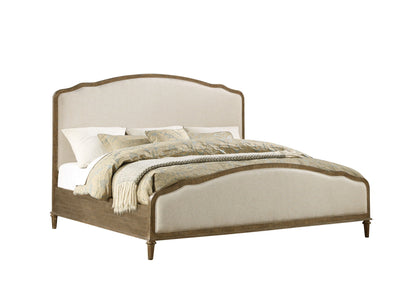 The Ludin - Upholstered Bed features a wooden frame with an upholstered headboard and footboard, styled in white and light beige bedding with patterned pillows and a neatly folded blanket.