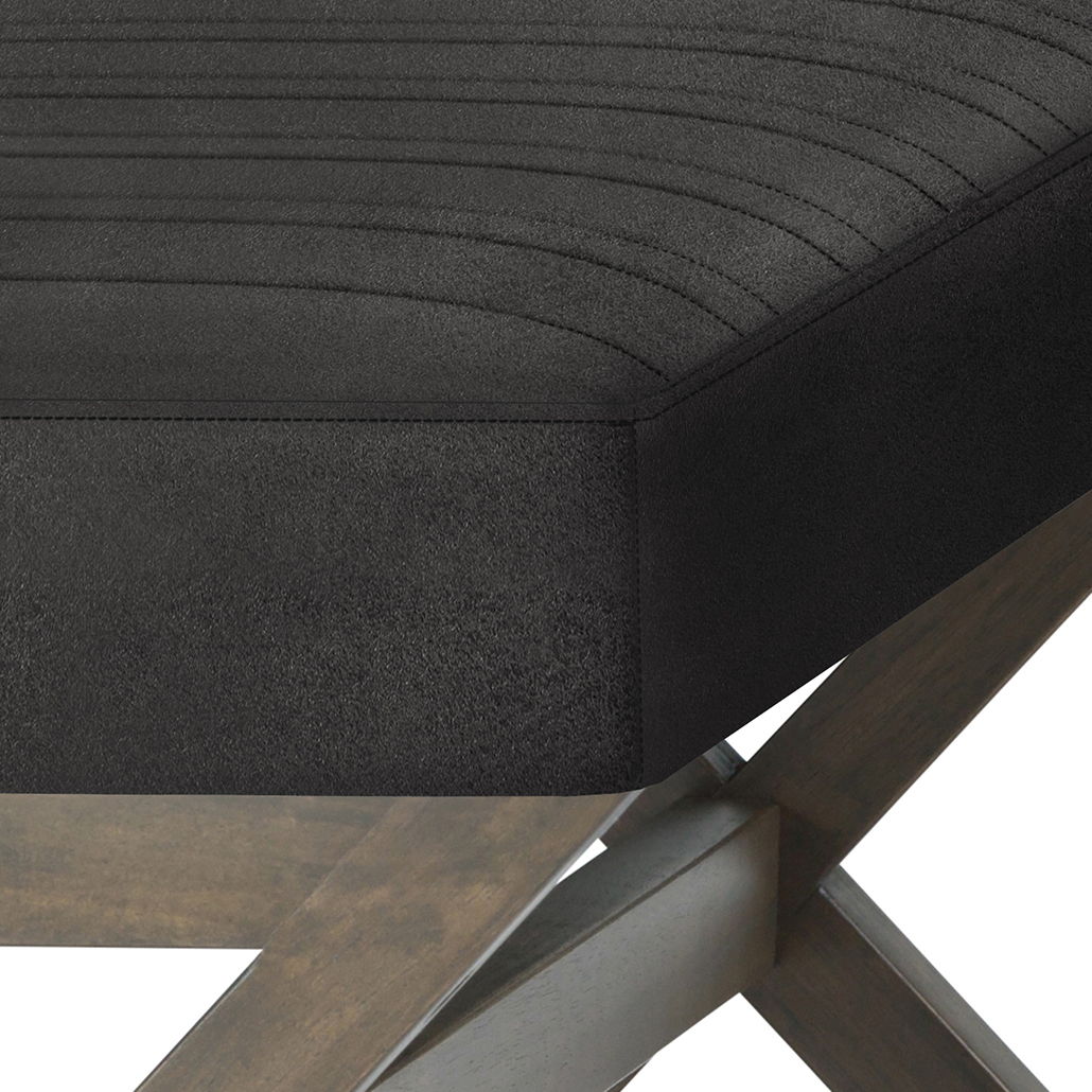 Close-up of the Salinger Large Upholstered Ottoman Bench showing its black, stitched seat and light brown crossed wooden legs.