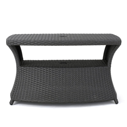 The Berkeley - Chaise Lounge Side Table features a rectangular, dark brown woven wicker design with curved sides, an open shelf under the tabletop, and stands on four legs.