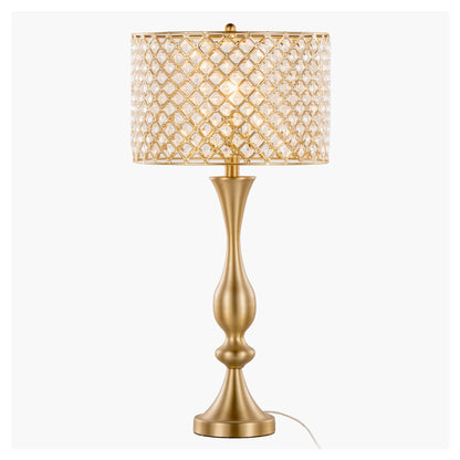 The Topaz - Contemporary Table Lamp features a gold sculpted base and a cylindrical lampshade with a diamond lattice design, shown illuminated against a plain white background.