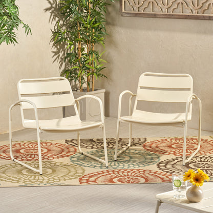 Two Conrad - Chair Outdoor Seating pieces in white sit on a patterned floral rug. Nearby are potted plants, a small table with sunflowers, and drinks in a bright, modern indoor space.