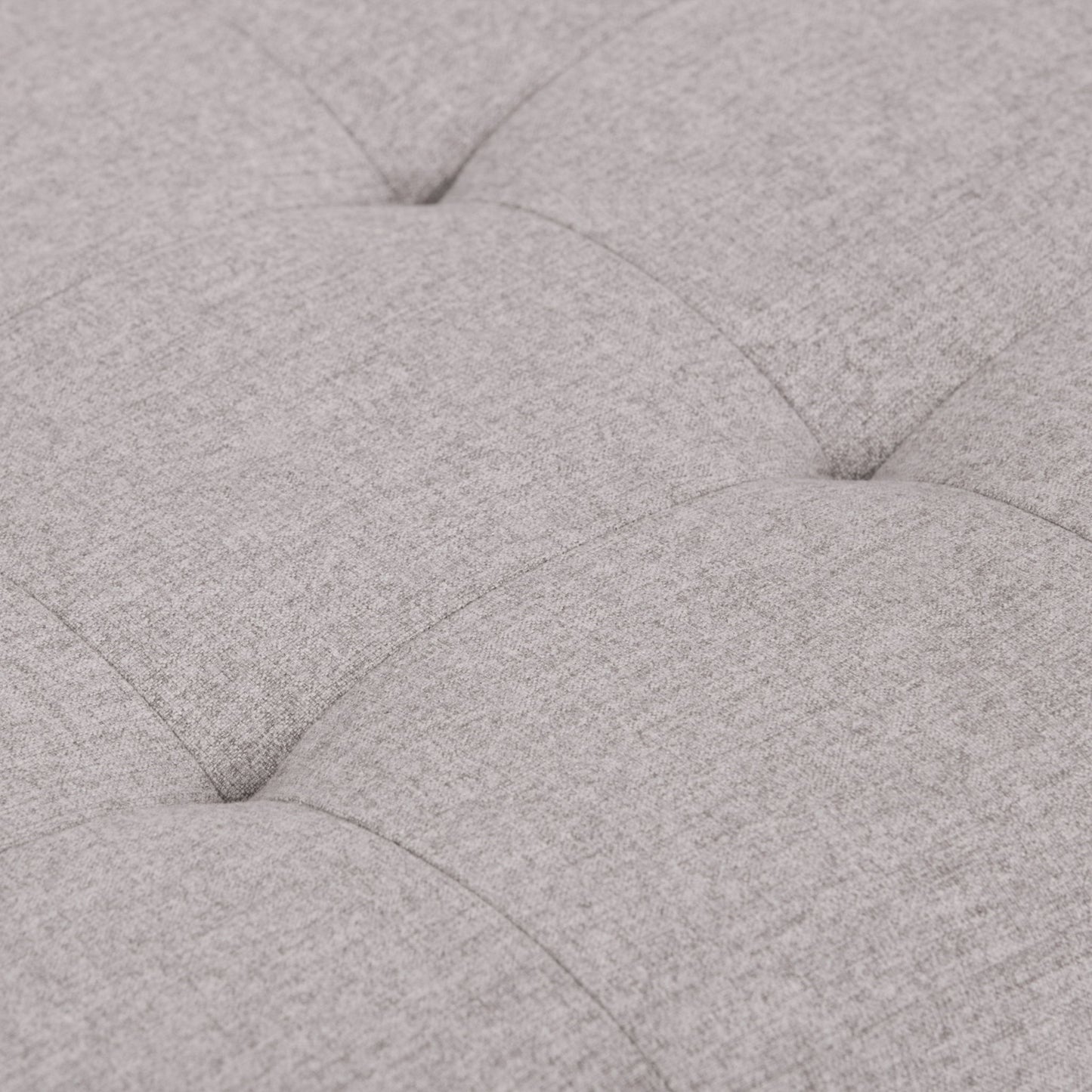 Close-up of the Cosmopolitan Upholstered Storage Ottoman in light gray, highlighting its soft tufted fabric, cushioned texture, and visible stitching with indented seams creating a grid pattern.