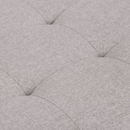 Close-up of the Cosmopolitan Upholstered Storage Ottoman in light gray, highlighting its soft tufted fabric, cushioned texture, and visible stitching with indented seams creating a grid pattern.