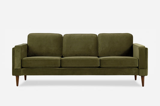 The Albany Sofa is a modern olive green velvet piece with three seat and back cushions and tapered wooden legs, displayed against a plain white background.