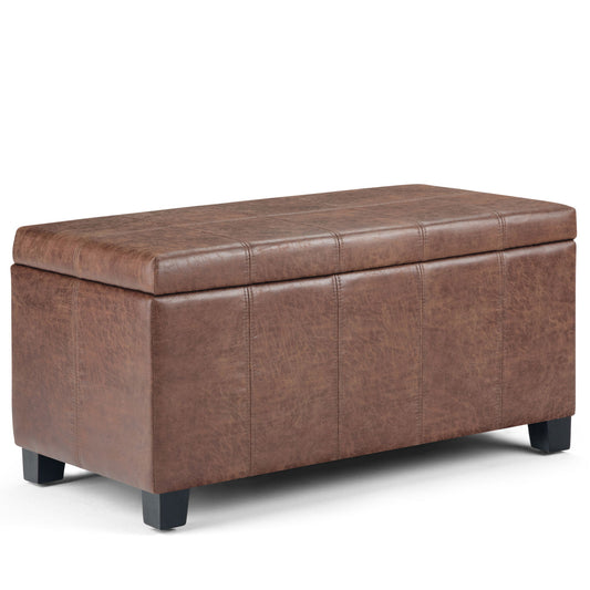 The Dover Upholstered Storage Ottoman Bench is a rectangular brown leather bench with a cushioned, lift-top lid, short black legs, visible stitching, and a slightly textured finish.