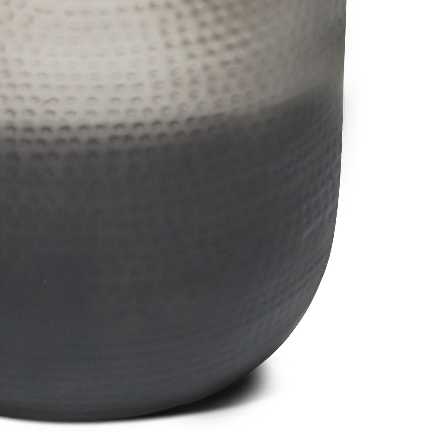 A close-up of the Nova - Handcrafted Metal Side Table reveals its rounded form, subtle dimpled texture, and a smooth gradient finish transitioning from light gray at the top to dark gray at the base.