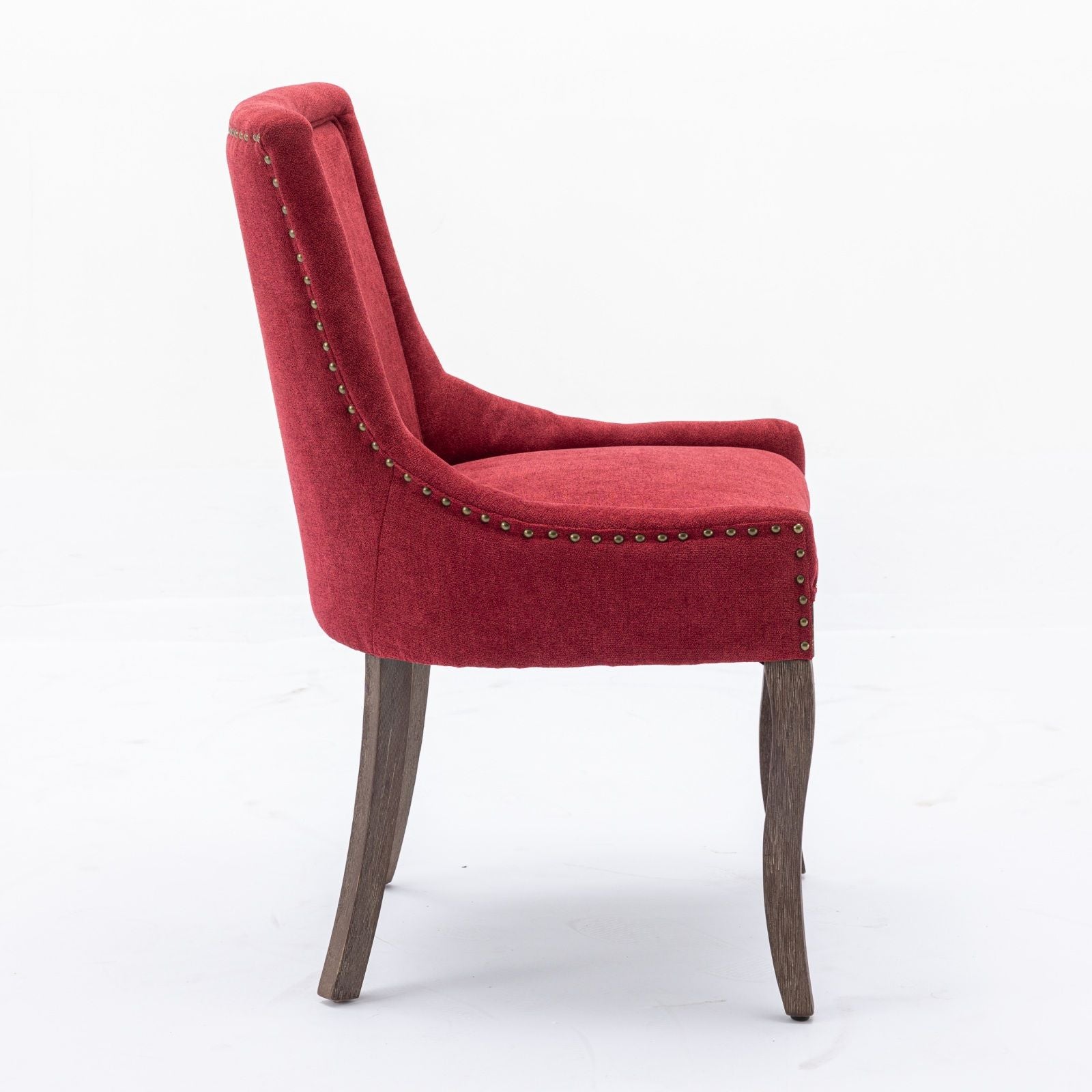 The Ultra Side Dining Chair features thickened red fabric, neutrally toned solid wood legs, and bronze nail head trim along the edges, shown from the side against a plain white background. Comes as a set of 2.
