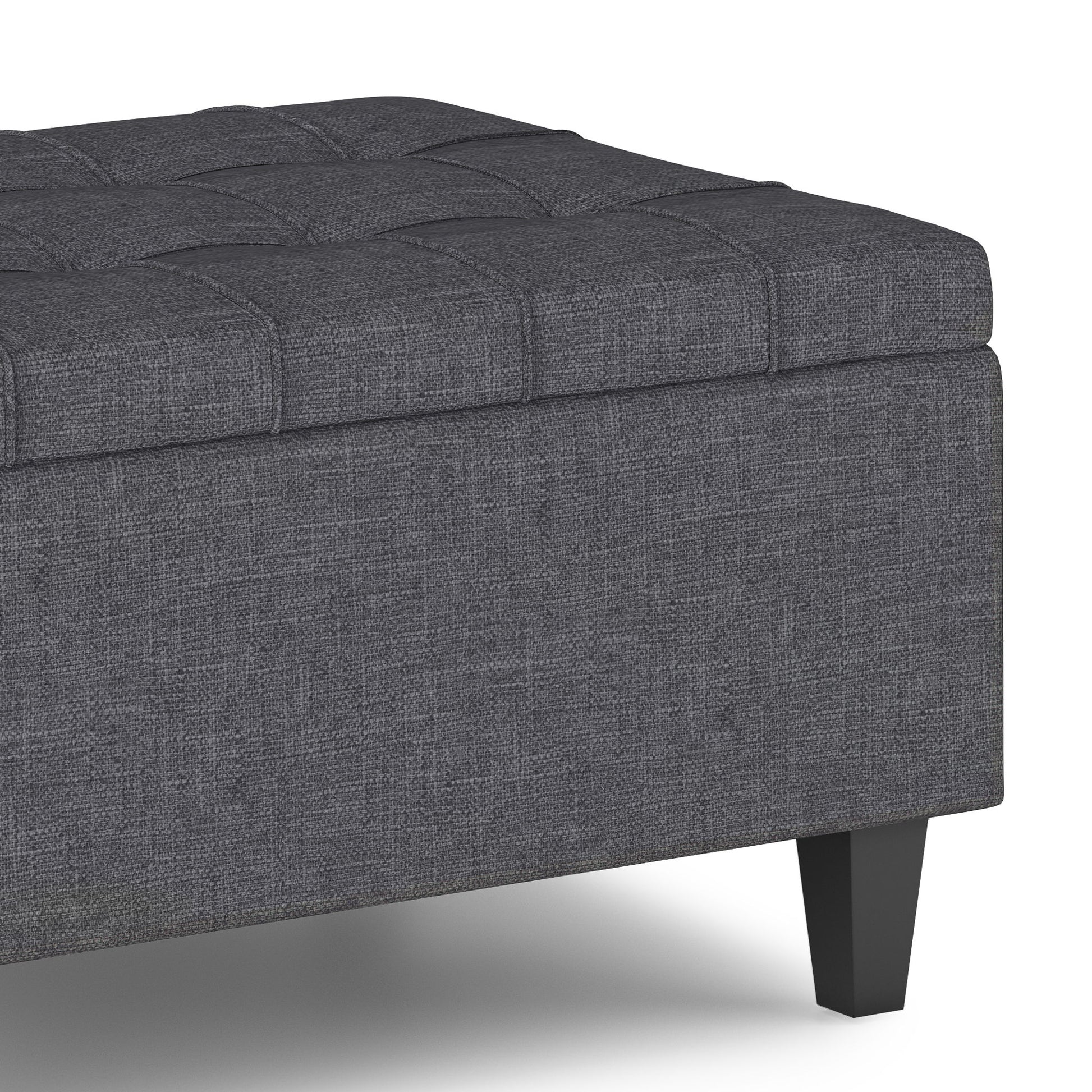 A close-up of the Harrison Upholstered Coffee Table Storage Ottoman in dark gray, featuring tufted detailing and black wooden legs, shown on a white background.