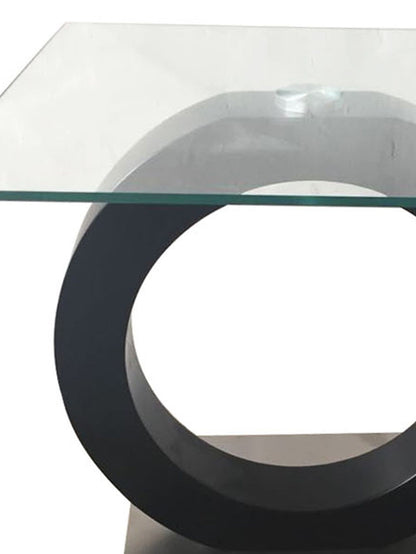 The Everest - Stylish Design Table features a geometric, minimalist design with a square glass top and a round black base, offering a modern look.