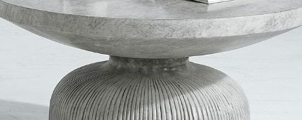 A close-up of the Laddie - Weathered Table, a modern round concrete coffee table featuring a thick, textured pedestal base and smooth tabletop.