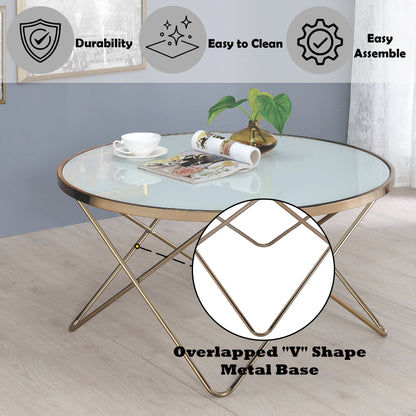 The Valora Glass Coffee Table features a round glass top and a gold overlapped "V" metal base on light wood flooring, adorned with a plant, teacup, and magazine. Icons show its durability, easy assembly, and simple cleaning.