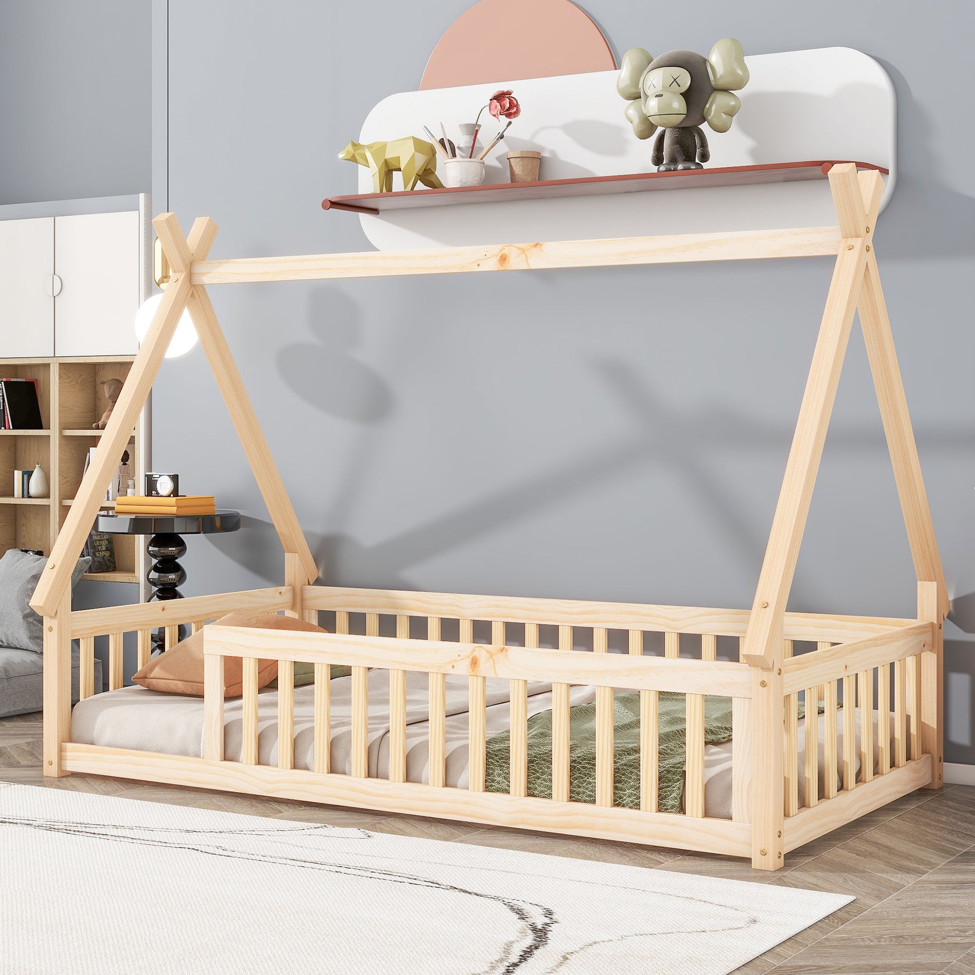 A Tent-Shaped Floor Bed with guardrails and slats sits in a modern children's room. The teepee-style bed is placed on a soft rug, while a shelf above displays decorative toys and books, creating a cozy, minimalistic space.