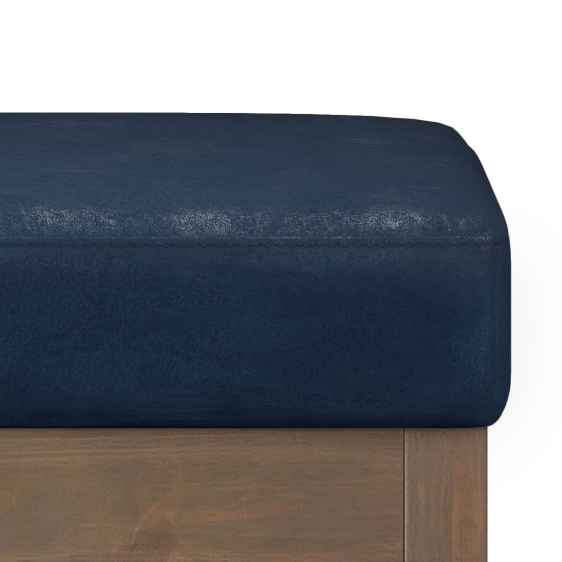 A close-up of the Milltown - Upholstered Ottoman Bench features its dark blue cushioned seat and wooden frame, highlighting corner and edge details against a white background.