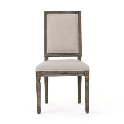 Front view of the Traditional Style Dining Chair Set With Fabric Upholstery featuring a rectangular, padded beige fabric seat and backrest, carved leg detailing, and weathered wood finish.