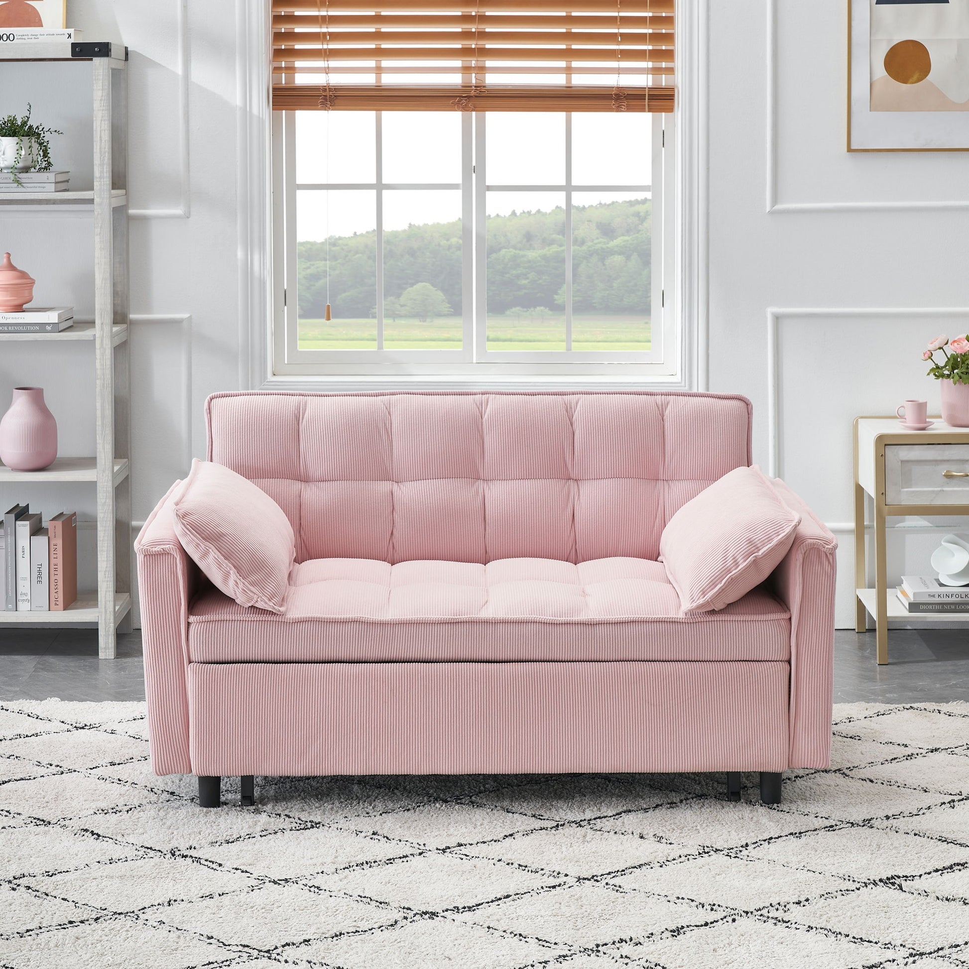 A Folding Sofa Bed With Adjustable Back, used as a loveseat with tufted cushions and matching pillows, sits on a patterned rug in a bright room featuring a window, shelves, and modern decor.