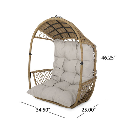 The Malia Wicker Hanging Chair With Cushion features an arched top, woven sides, and a beige cushioned seat and back. Dimensions: 46.25" H x 34.5" W x 25" D.