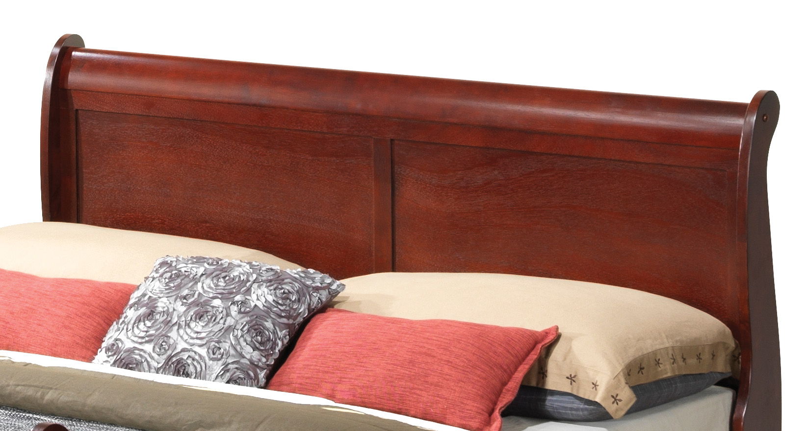 A Panel Sleigh Bed with a wooden headboard in dark cherry finish is shown with a beige pillow, a patterned pillow, and red pillows neatly arranged on the bed.