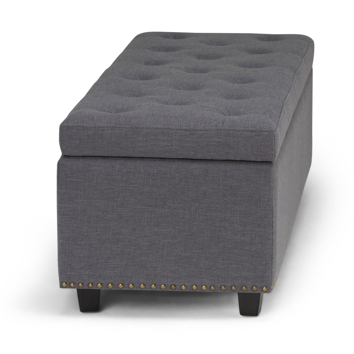 The Hamilton Upholstered Storage Ottoman features a rectangular gray design, tufted top, dark wood legs, and brass nailhead trim along the bottom edge.