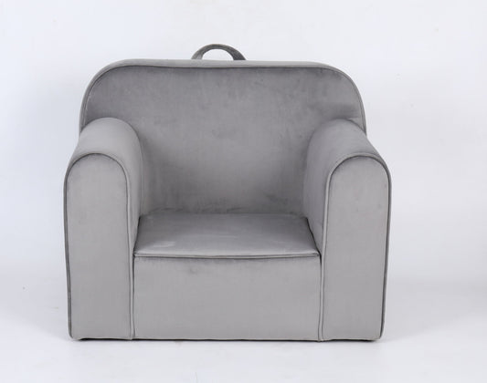 The Durable Design Kids Club Sofa is a small, light gray upholstered armchair with rounded arms, a slightly curved backrest, and a fabric handle at the top for easy carrying. It is shown against a plain white background.