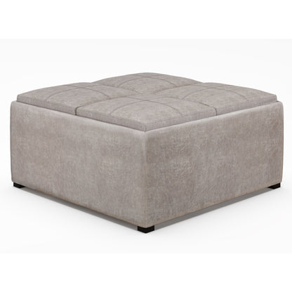 The Avalon Square Coffee Table Storage Ottoman features a large, light gray upholstered design with a tufted top and low black feet, shown against a plain white background.