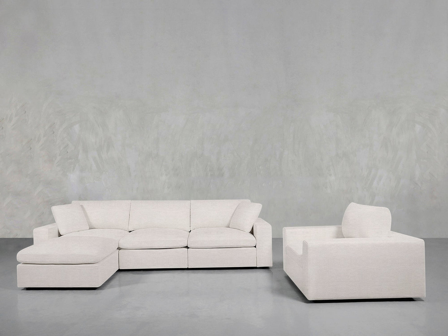 The 4-1 Sectional & Armchair Set features a light beige sectional and matching armchair, arranged on a gray floor with a textured light gray wall backdrop for a modern living room look.