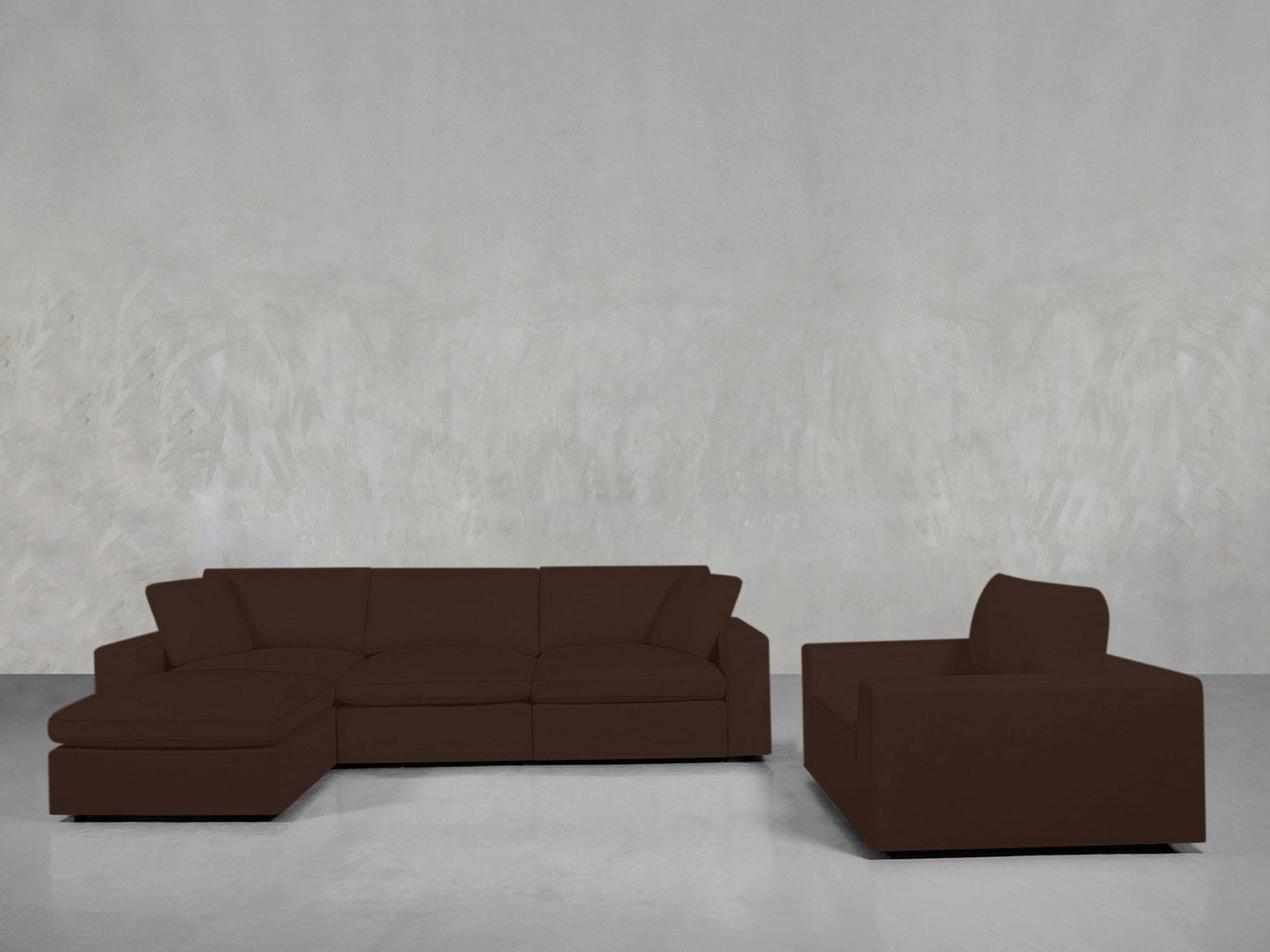 The 4-1 Sectional & Armchair Set, featuring a brown sectional with left chaise and a matching armchair, is arranged against a plain light gray textured wall and a bare floor.