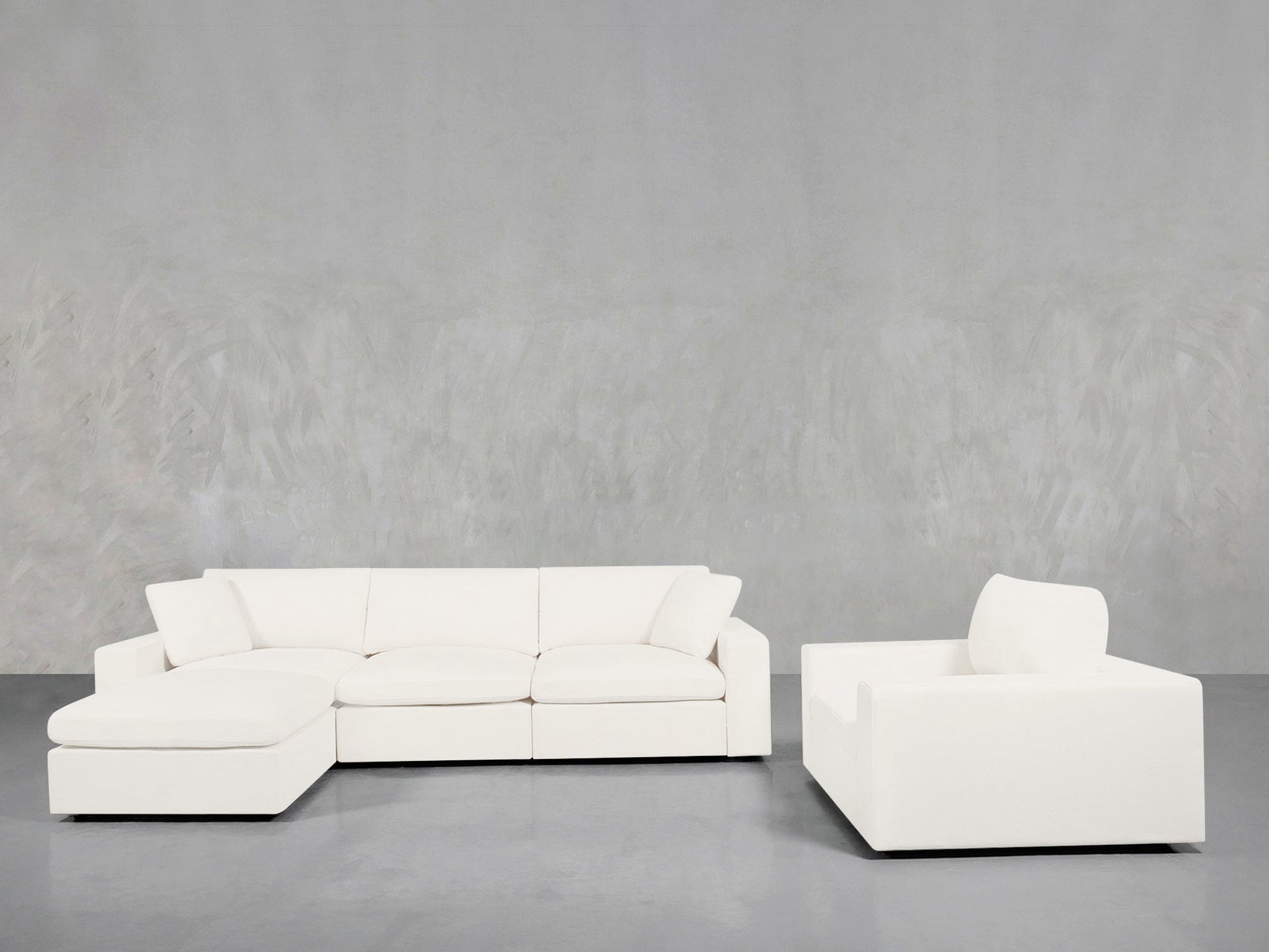 A modern, minimalist living room featuring the 4-1 Sectional & Armchair Set in white, set against a light gray wall and polished gray floor.