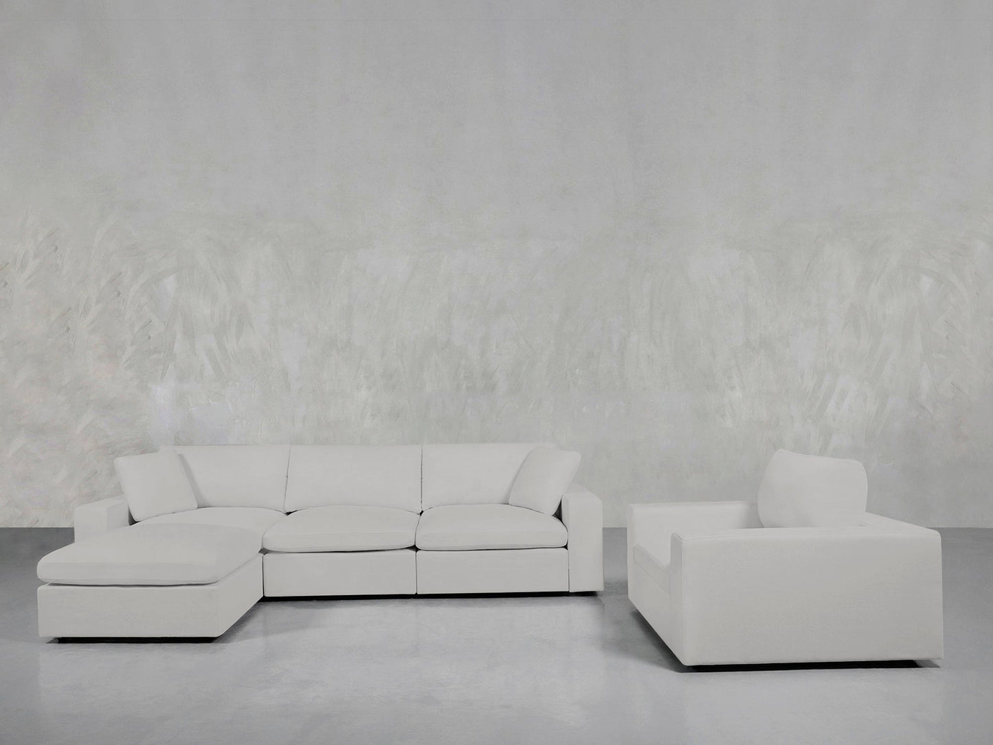 The 4-1 Sectional & Armchair Set features a large white sectional and matching armchair, stylishly arranged on a light gray floor with a textured light gray wall for a modern living room look.