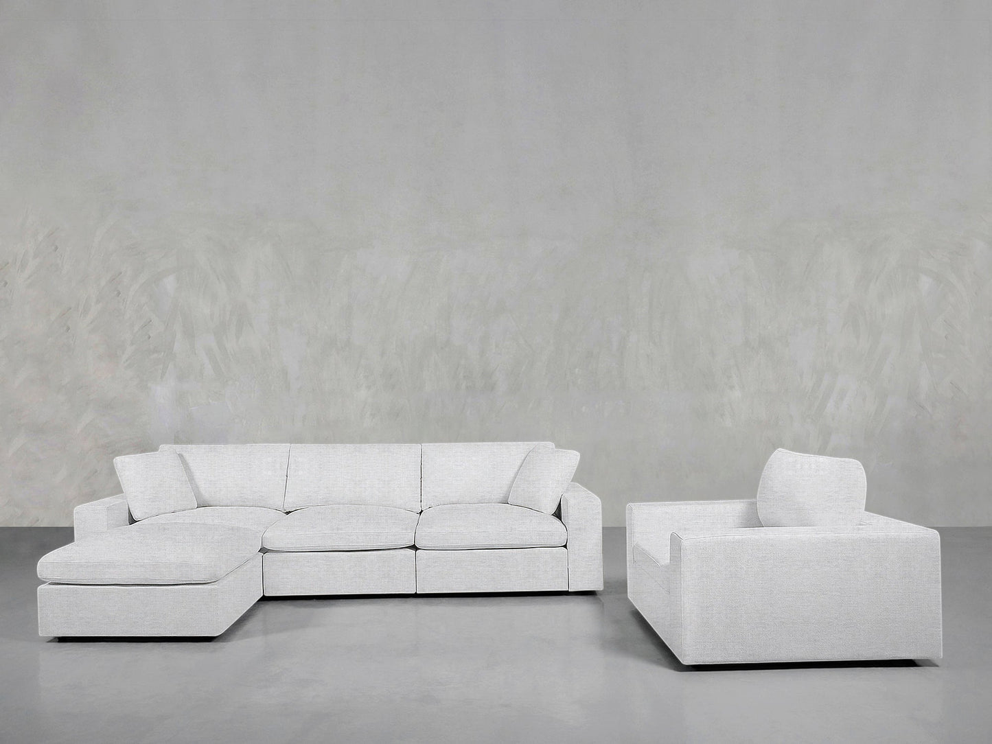 The 4-1 Sectional & Armchair Set features a modern light gray sectional with a left chaise lounge and matching armchair, arranged against a plain textured gray wall and smooth gray floor.