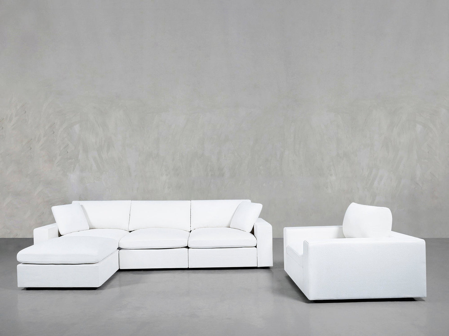 A modern minimalist living room showcasing the 4-1 Sectional & Armchair Set in white, with a left-facing chaise sectional and matching armchair on a gray floor against a light gray textured wall.
