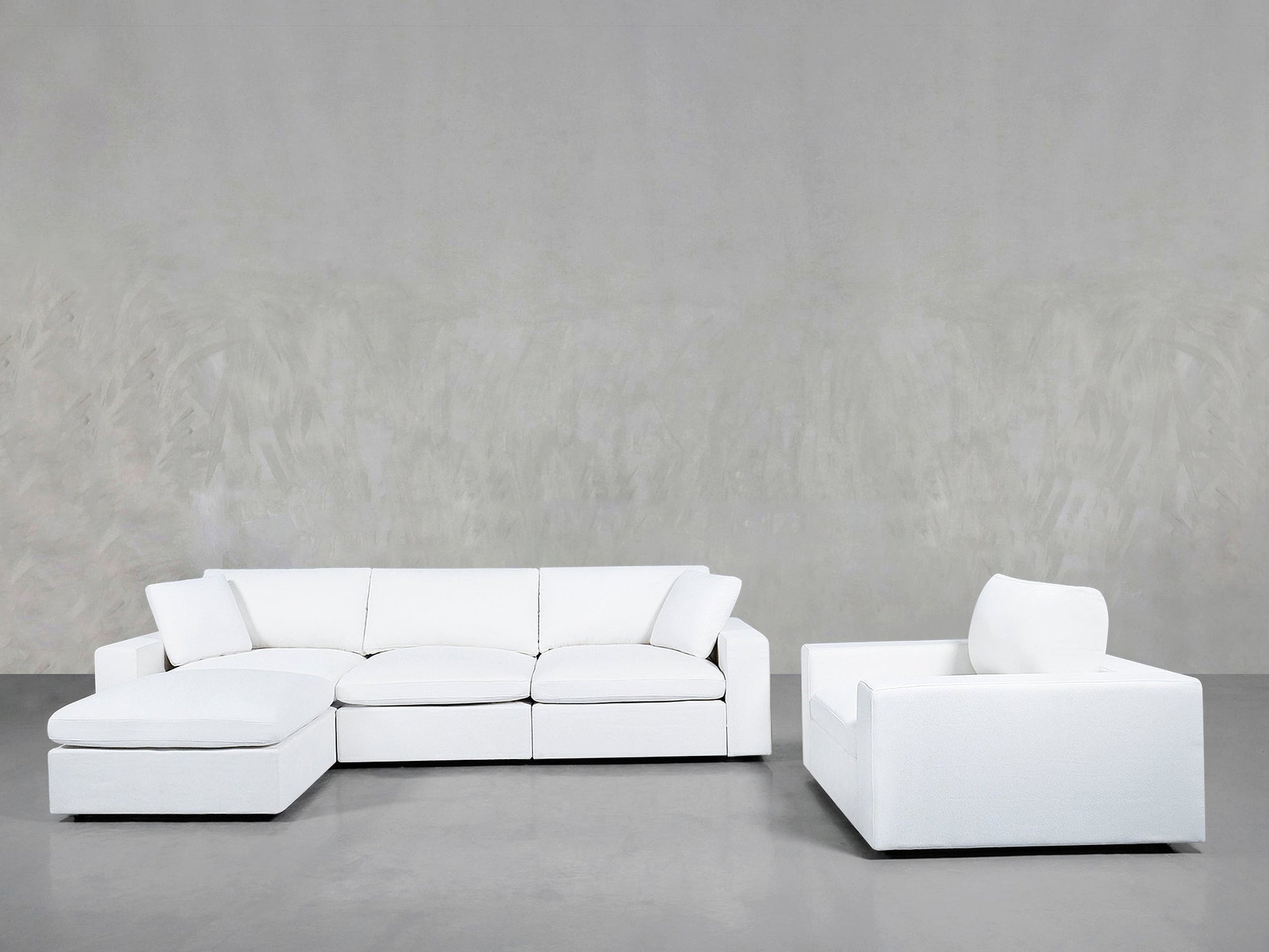A modern minimalist living room showcasing the 4-1 Sectional & Armchair Set in white, with a left-facing chaise sectional and matching armchair on a gray floor against a light gray textured wall.