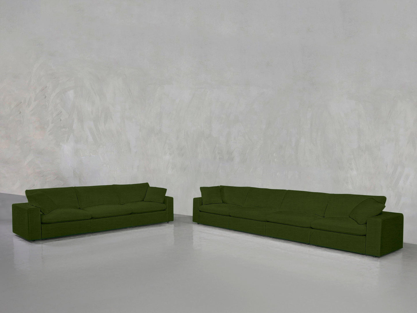 The 4-3 Sofa Set, featuring two modern green sofas with boxy shapes, is arranged on a shiny light gray floor against a textured light gray wall in a minimalist room.