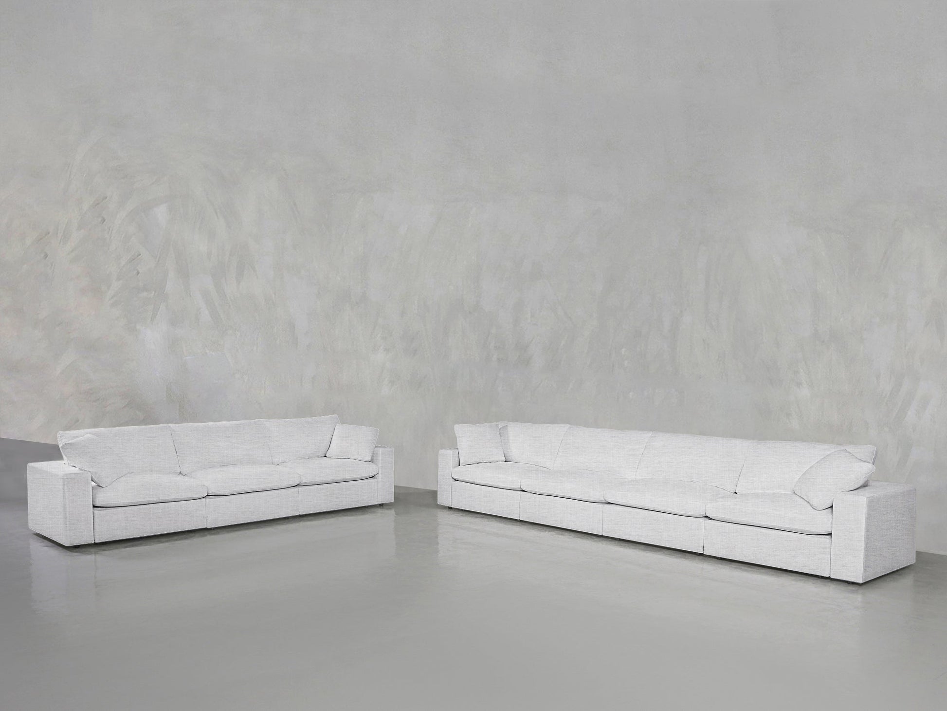 The 4-3 Sofa Set features two modern, minimalist white sofas with clean lines, placed on a glossy gray floor against a textured light gray wall in a spacious, empty room.