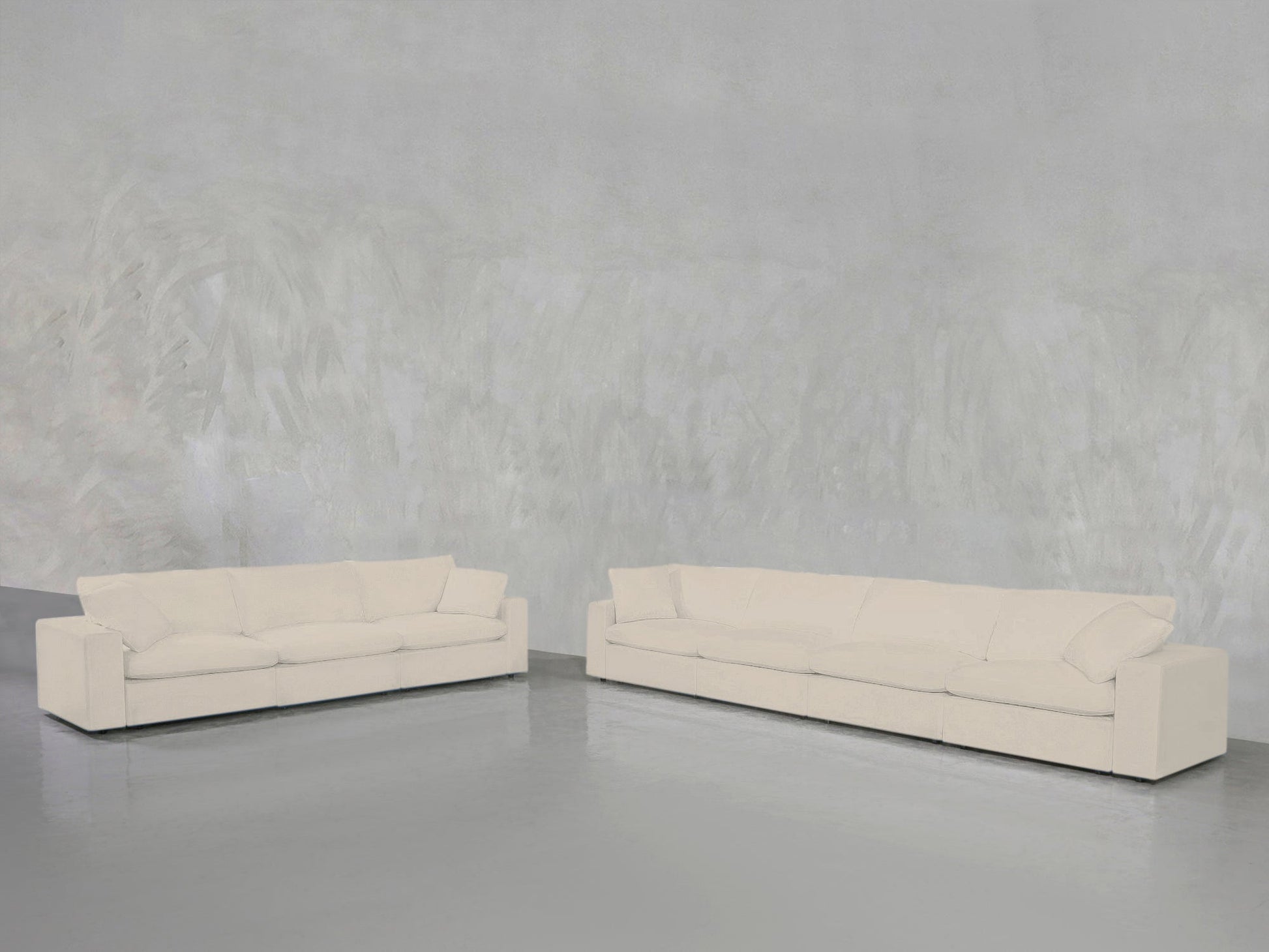 The 4-3 Sofa Set, featuring two modern cream sofas with square arms, is arranged against a light gray textured wall and glossy gray floor in a minimalist open space.