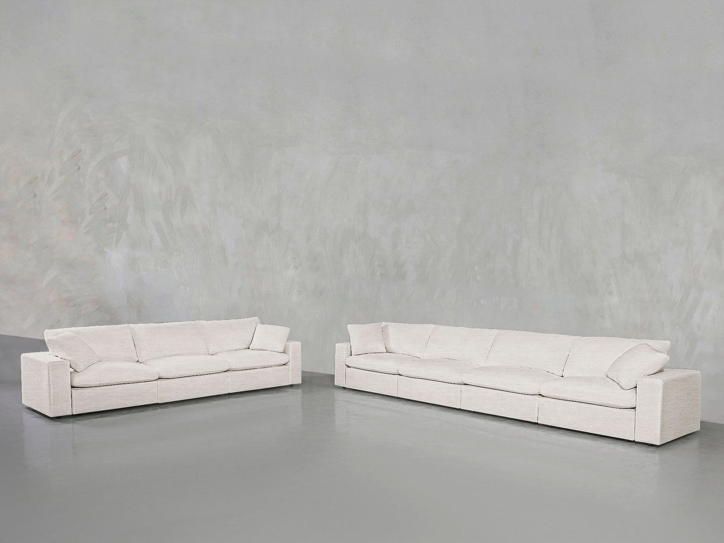The 4-3 Sofa Set, featuring two modern off-white sofas with clean lines, is arranged in a minimalist room with a light gray textured wall and a smooth gray floor.