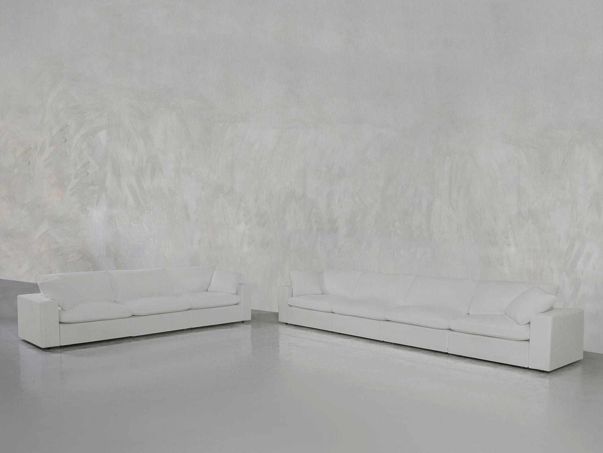 Two 4-3 Sofa Sets in modern white are arranged in a minimalist room with a light gray textured wall and smooth gray floor, creating a spacious and serene atmosphere.