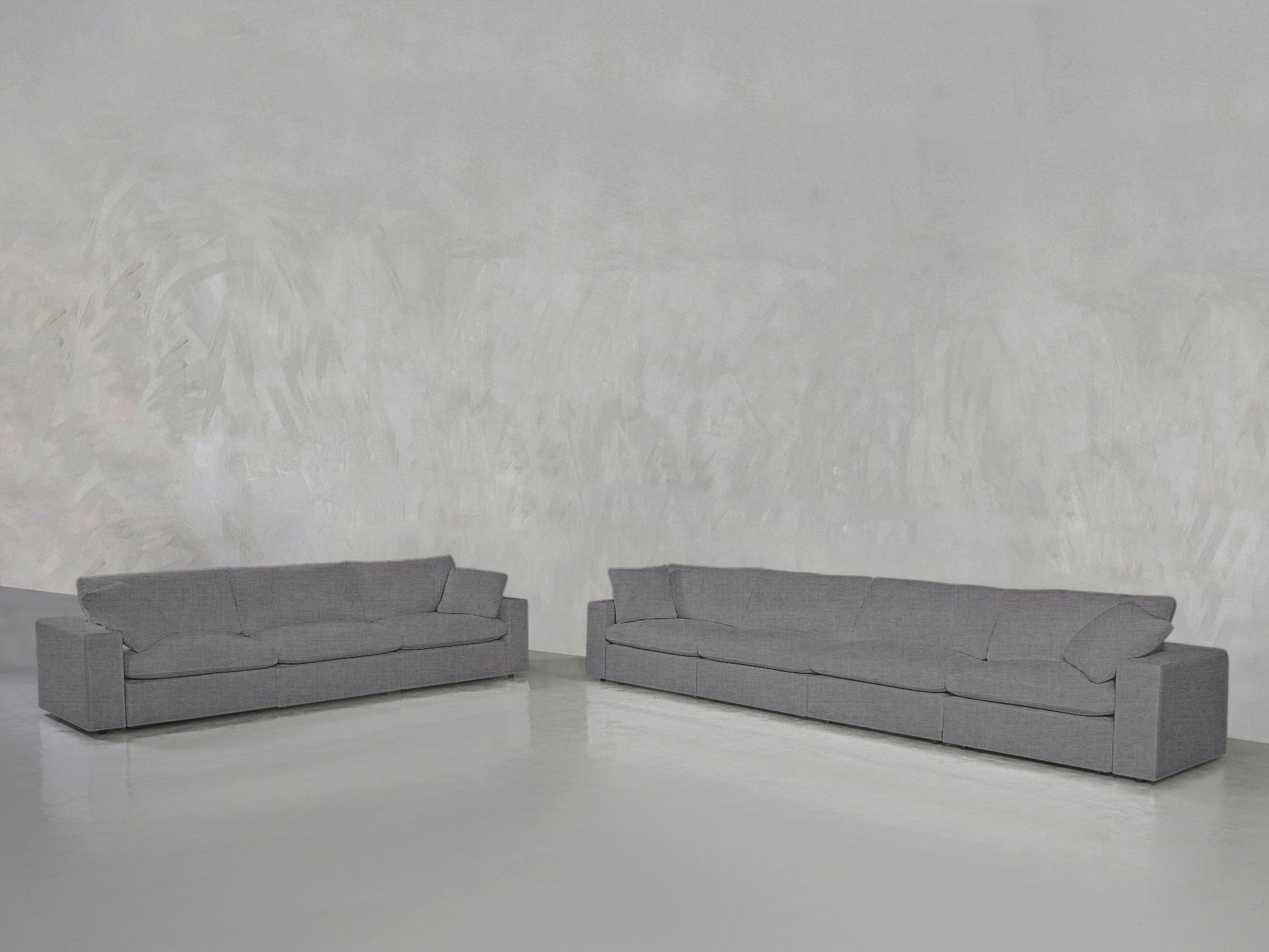 The 4-3 Sofa Set in modern gray is arranged against a light gray textured wall and glossy floor, creating a minimalistic, spacious atmosphere.