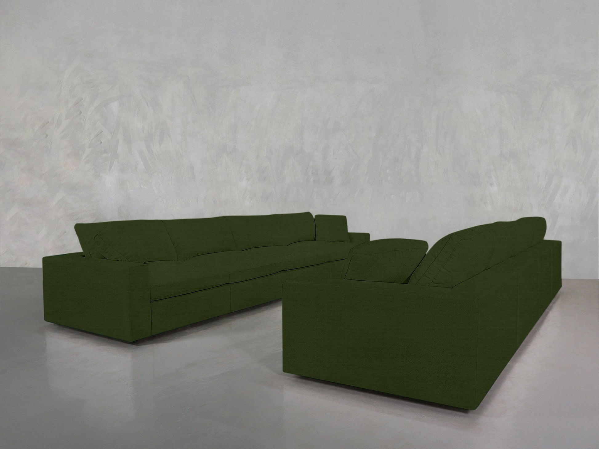 The 4-4 Sofa Set features two dark green, modern, boxy sofas arranged in an L-shape in a minimalist room with textured light gray walls and a polished gray floor.