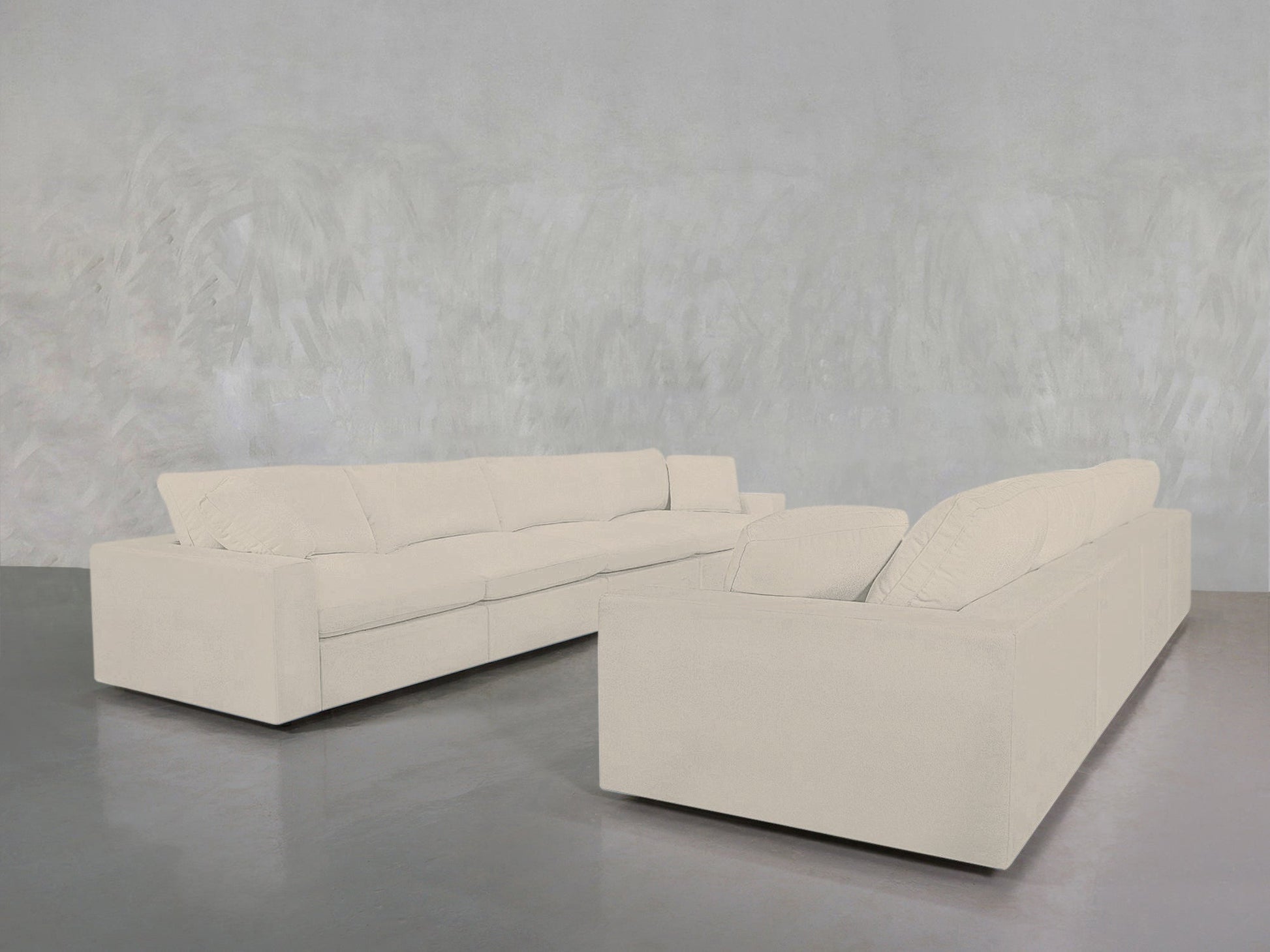 Two 4-4 Sofa Sets in cream sit on a gray polished floor against a textured light gray wall, creating a minimalistic, modern look.