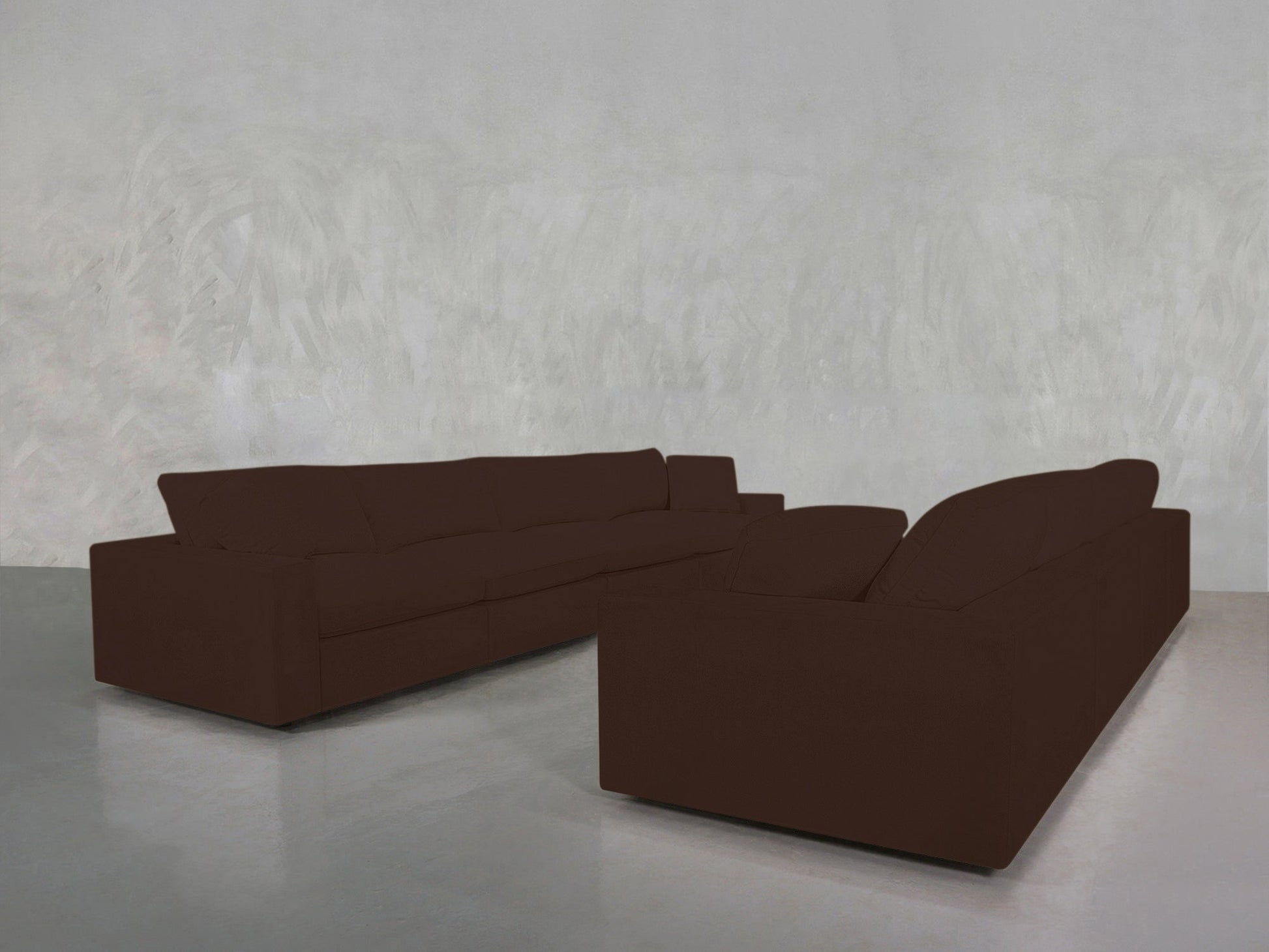 Two 4-4 Sofa Sets in dark brown are arranged facing each other in a minimalist room with light gray textured walls and a shiny gray floor.