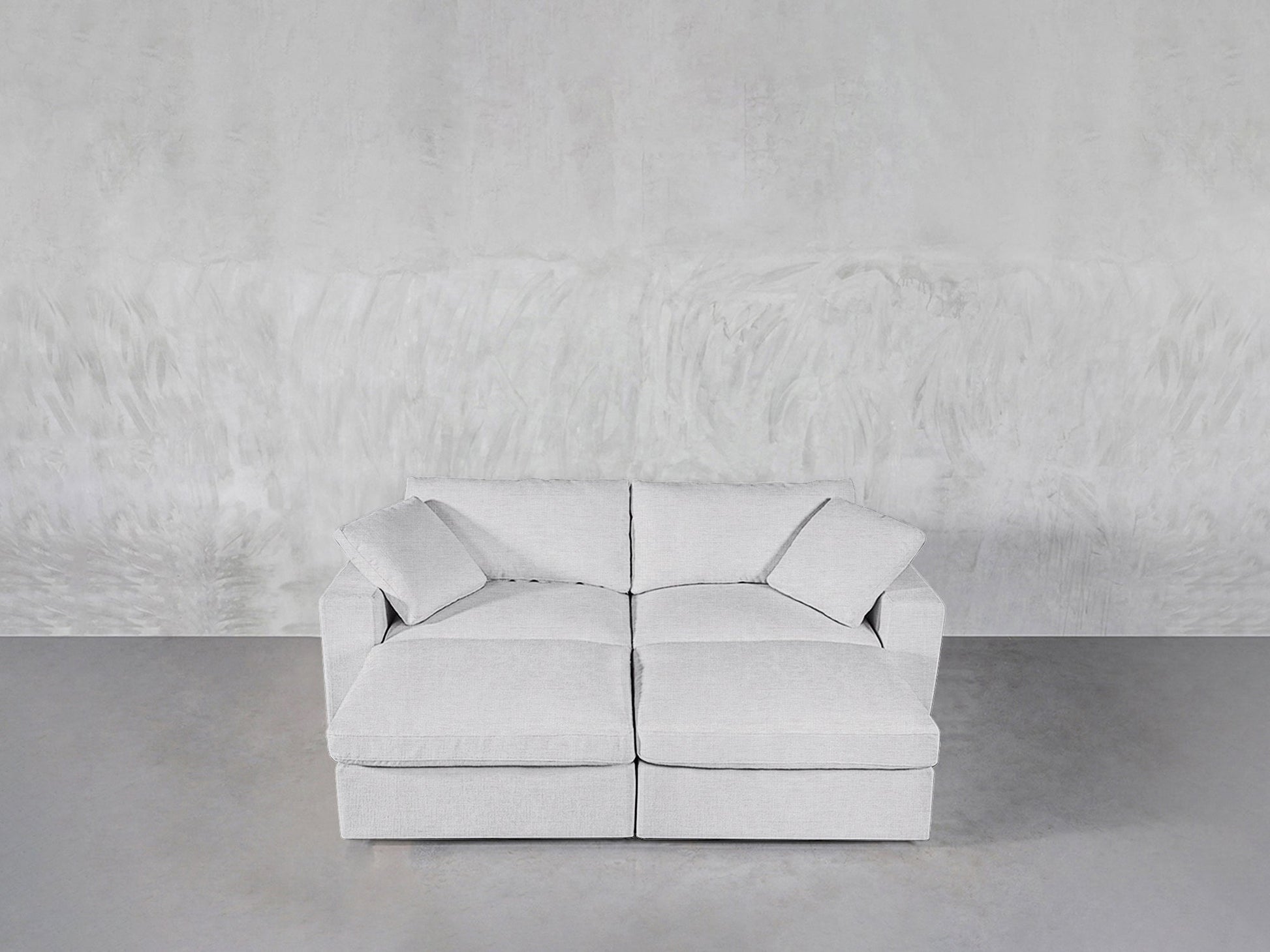 A modern light gray 4-Seat Modular Daybed sits against a textured light gray wall on a smooth gray floor.