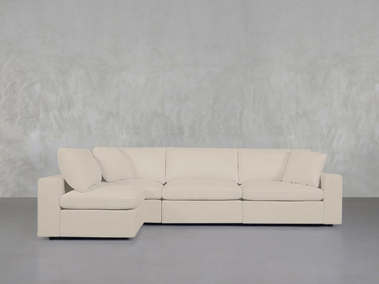 A 4-Seat Modular Open Corner Sectional in light beige with a chaise lounge is set against a textured light gray wall and gray floor, creating a minimalist and contemporary atmosphere.