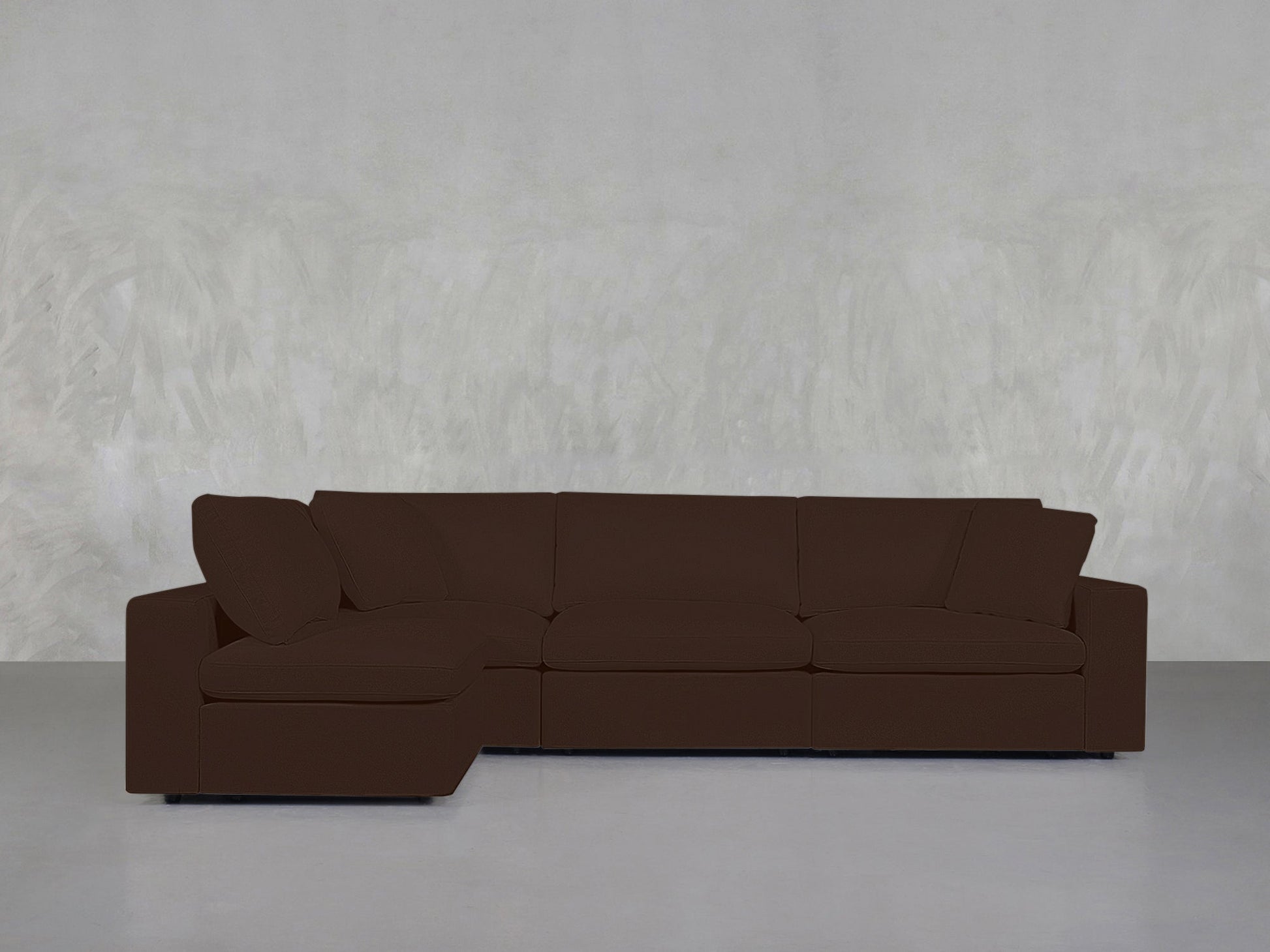 A 4-Seat Modular Open Corner Sectional with a chaise on the left, set against a light gray textured wall and placed on a smooth, light-colored floor.