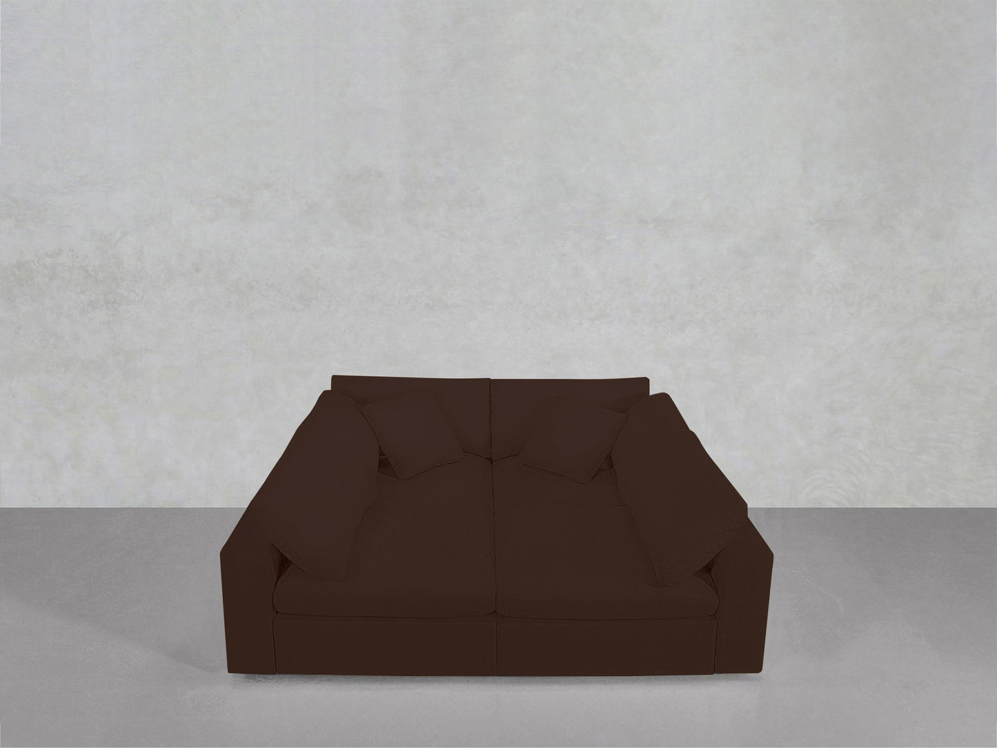 A dark brown 4-Seat Modular Pit with cushions is positioned against a plain, light gray wall on a smooth gray floor.