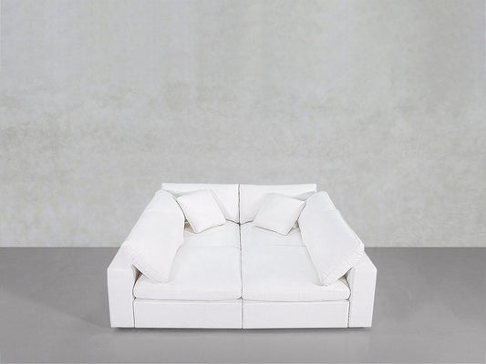 The 4-Seat Modular Pit is a modern white sofa featuring two seat cushions, two back cushions, and four square pillows, shown against a plain light gray wall and gray floor.