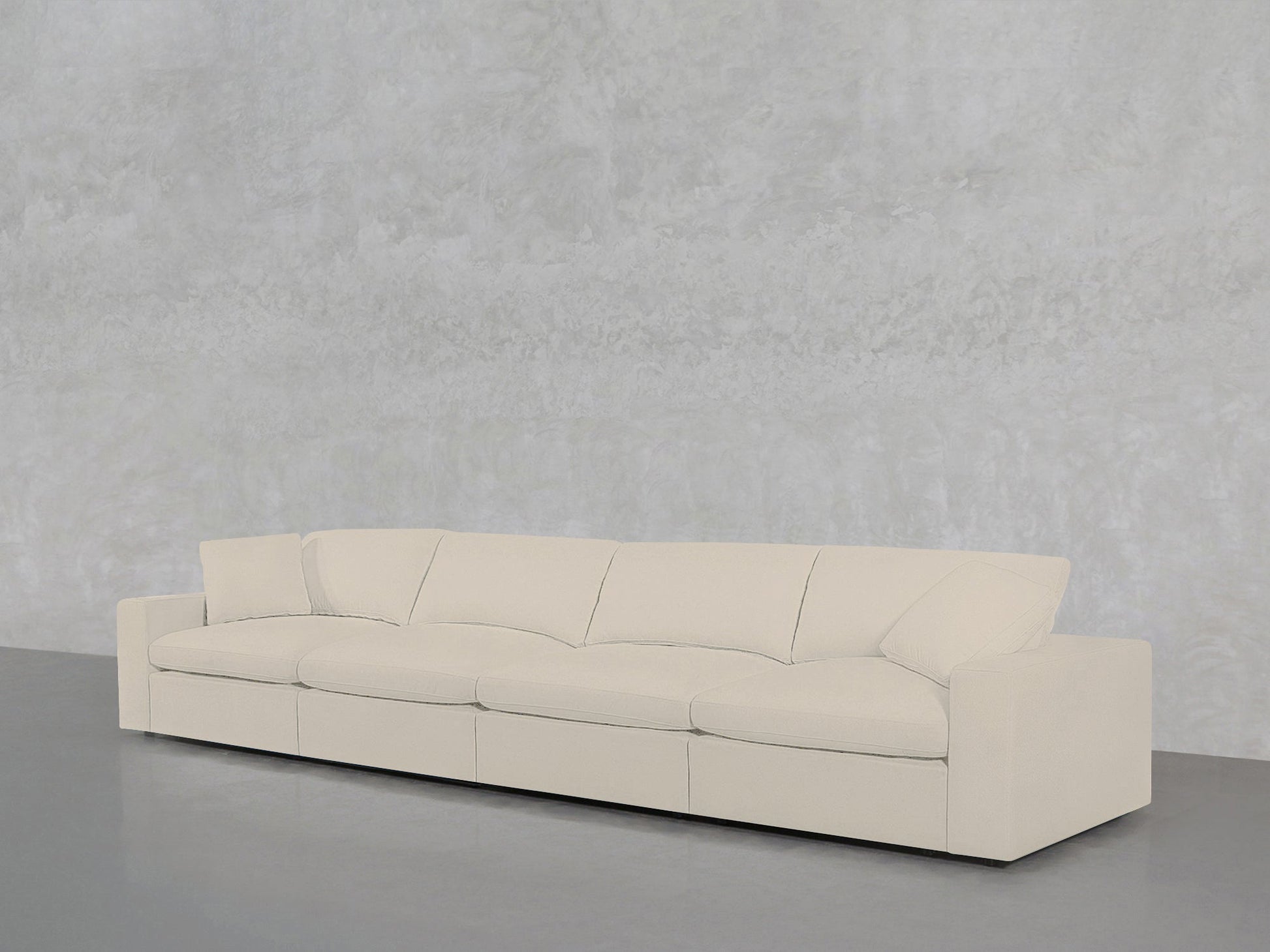 A 4-Seat Modular Sofa in cream is positioned against a light gray textured wall on a smooth gray floor.